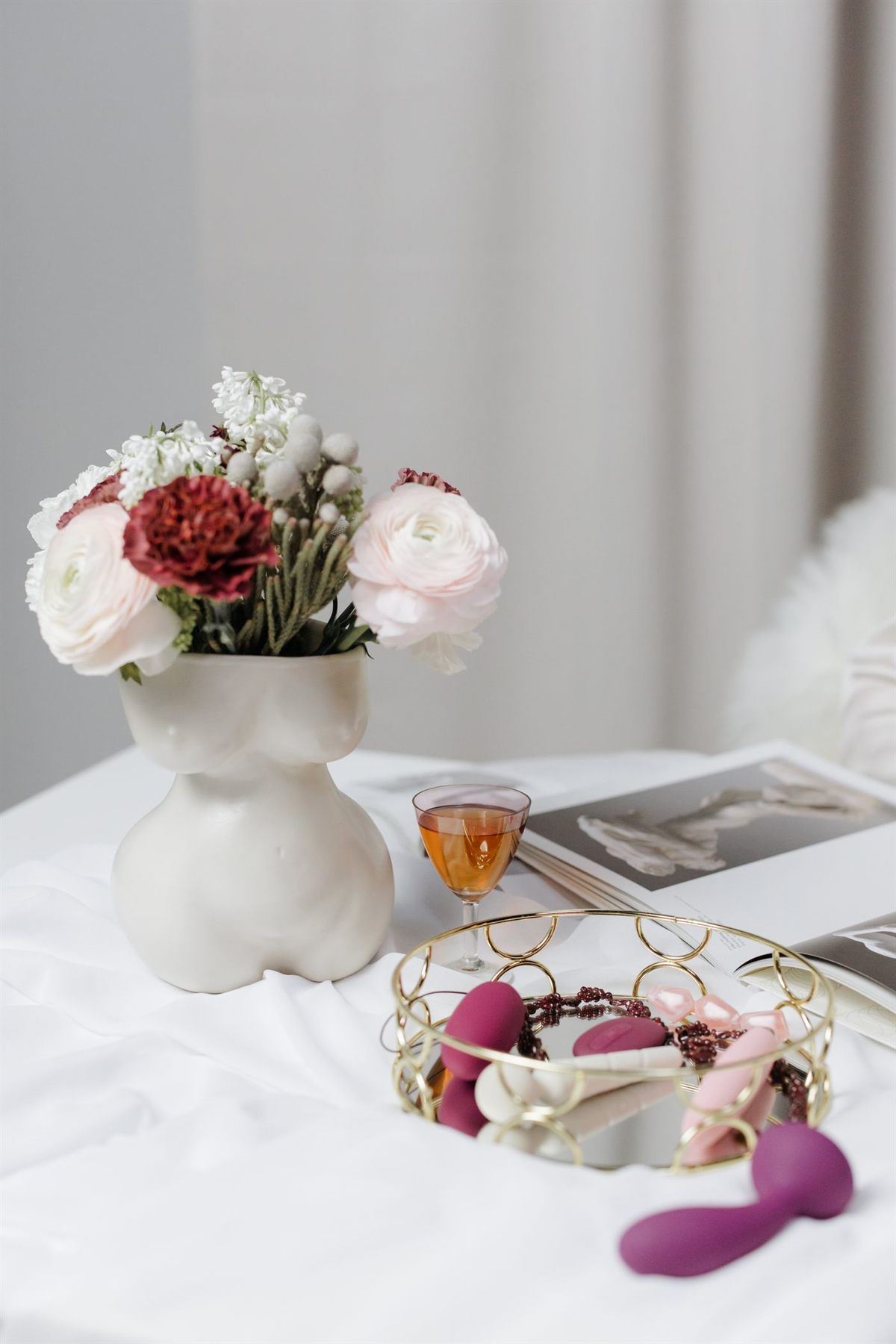 Body-safe intimate toys styled with flowers on a nightstand